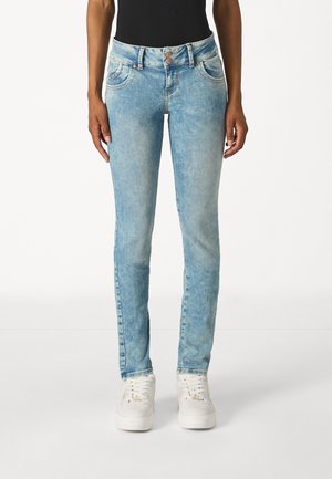 Light blue denim jeans with a slim fit, mid-rise waistband, five-pocket design, and subtle fading. Paired with white sneakers.