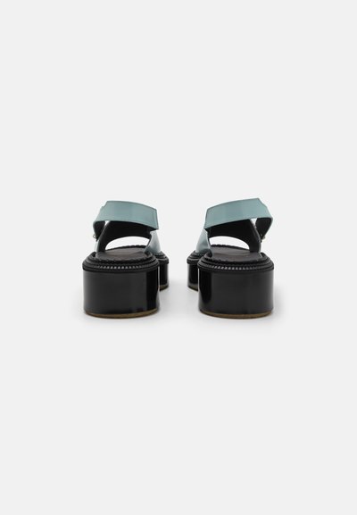 Sorte platform sandaler med tykke hæle, med en bred turkis stropp og et åbent bagdesign, lavet af glat, blankt materiale.