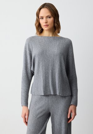 Grijze geribbelde gebreide trui met een brede bootnek en lange mouwen, met een losse pasvorm en subtiele textuur. Gecombineerd met bijpassende broek.
