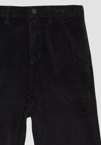 Zwarte corduroy broek met verticale ribbels, voorzien van een knoopsluiting en schuin geplaatste zijzakken. Gladde textuur met een getailleerd ontwerp.