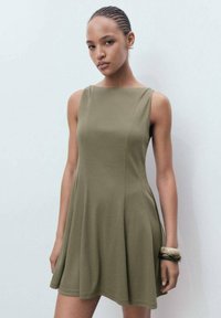 Rochie fără mâneci de culoare verde măslin, fabricată dintr-un material moale, cu o formă în A, de lungime sub genunchi, prezentând detalii subtile de cusătură și o textură netedă.