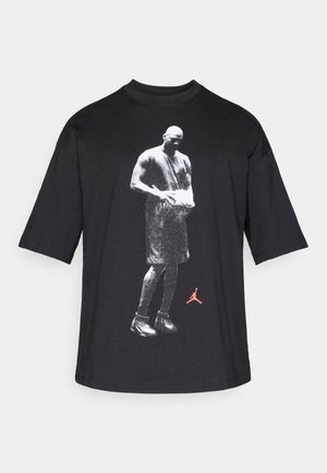 Tricou negru din bumbac cu mâneci scurte, cu o grafică monocromă a unui jucător de baschet și un logo Jordan roșu pe partea din față.