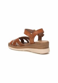 Sandalo wedge in pelle marrone con suola dall'aspetto legnoso, caratterizzato da più cinturini incrociati e dettagli perforati. Include una fibbia regolabile alla caviglia.