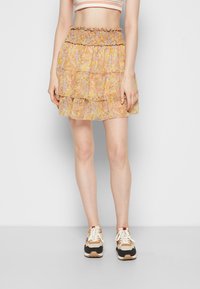 Saia mini em camadas com padrão floral e cintura franzida, apresentando tons de amarelo, rosa e azul. Tecido leve e fluido.