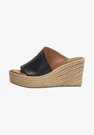 Zwarte leren sleehakken met een brede band over de voet, een jute-wrapped middenzool en een gladde bruine voetbed.