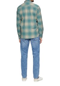 Geruite shirt in teal, beige en blauwe tinten; lange mouwen; knoopsluiting bij de kraag; textuurstof; gedragen met lichtblauwe jeans en witte sneakers.