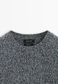 Szary sweter z kaszmiru z okrągłym dekoltem, wykonany z teksturowanej dzianiny, z metką zawierającą informację "Massimo Dutti" oraz instrukcje pielęgnacji.