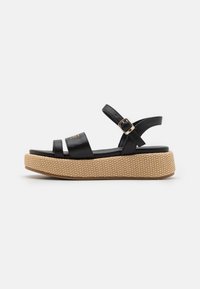 Black leather platform sandals with three straps, adjustable ankle buckle, and textured woven midsole. Rubber outsole for grip.