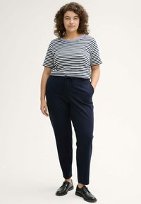 Camiseta de manga corta a rayas en azul marino y blanco con un cuello azul, combinada con pantalones navy ajustados con cintura con cordón y bolsillos laterales.