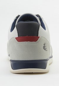 Weiße und graue Sneaker mit Navy- und Rotakzenten, ausgestattet mit einem strukturierten Obermaterial, gepolsterter Kragen und Gummisohle. Logodetail an der Ferse.