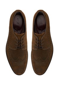Zapatos brogue de ante marrón con diseño de cordones, que presentan perforaciones decorativas y punta redonda. Superficie texturizada y suela negra.