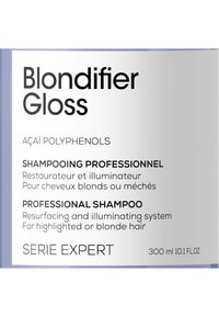 Botella de shampoo Blondifier Gloss, diseño elegante, etiqueta lila clara, texto en negro. Los detalles incluyen ingredientes y beneficios del producto. Tamaño de 300 ml.