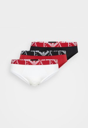 Trois paires de sous-vêtements : une blanche, une rouge et une noire. Chacune présente une ceinture élastique de marque avec logo et motifs rayés.