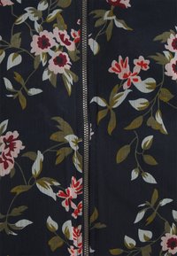 Květinová látka na zip má tmavé pozadí s bílými, růžovými a červenými květy; obsahuje zelené listy a kovový zip.