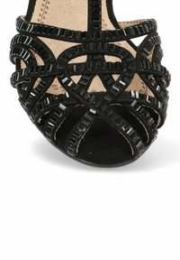 Sandal de tacón negro con intrincadas correas con acentos cuadrados, un suave forro interior y un diseño de puntera redondeada.