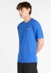 T-shirt pour homme à manches courtes de couleur bleu vif, en tissu respirant avec une texture subtile, arborant un petit logo sur le haut à gauche de la poitrine.