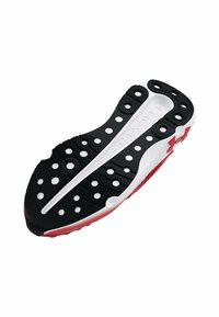 Suela de zapatilla deportiva en blanco y negro con acentos rojos, que presenta patrones circulares, superficie texturizada y áreas de agarre multidireccional distintivas.