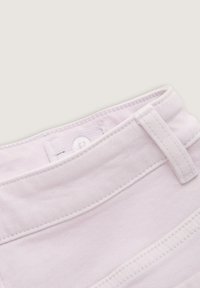 Un tessuto di denim rosa chiaro mostra un primo piano della cintura con dettagli delle cuciture e un bottone. Presenta passanti per cintura e una texture liscia.