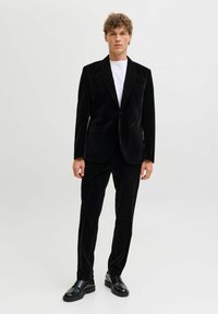 Čierny sametový oblek s klopou, ktorý má dve predné vrecká. Pár čiernych dress shoes s hladkým povrchom. Biely tričko pod ním.