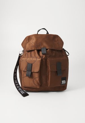 Brązowy plecak z tkaniny z kwiatowym wzorem, dwie przednie kieszenie z czarnymi paskami oraz czarna rączka z metką "marimekko".