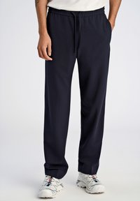 Pantalons de survêtement bleu marine avec une taille élastique et un cordon de serrage, dotés de poches latérales et d'une texture lisse et douce.
