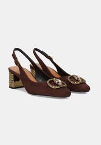 Tacones slingback de cuero ante marrón con punta cuadrada, adornados con una hebilla decorativa acentuada en oro y un tacón bloque texturizado en oro.