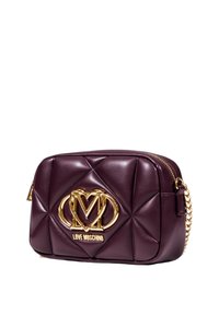 Borsa in pelle bordeaux trapuntata con un accento dorato del logo. Presenta una chiusura a zip e una tracolla a catena, con una forma rettangolare compatta.