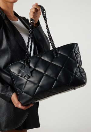 Czarna pikowana torba na ramię z materiału syntetycznego, z łańcuszkowymi uchwytami oraz zawieszką w kształcie gwiazdy z napisem "REBEL."