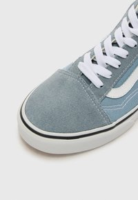 Helleblaue Canvas-Sneaker mit einer Wildleder-Spitze, weißen Schnürsenkeln, kontrastierender schwarzer Gummisohle und seitlichem Streifen-Detail.
