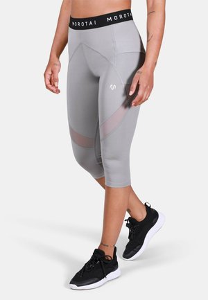 Leggings capri gris avec des panneaux en mesh, des coutures contrastées et une bande noire portant le logo "MOROTAI". Portés avec des chaussures de sport noires.