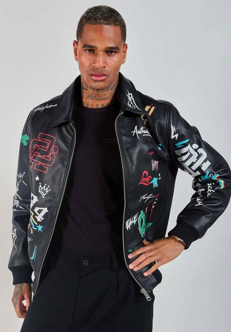 Veste bombardier en cuir noir avec des imprimés graphiques colorés et de la broderie. Dispose d'une fermeture éclair et de poignets côtelés. Design de col classique.