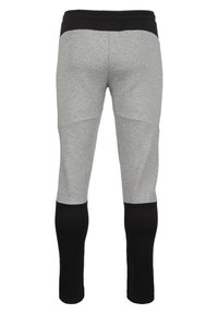 Grijze sportbroek met een zwarte elastische tailleband, voorzien van een kleurblokontwerp met zwarte accenten op de onderbenen en een gestructureerde stof.