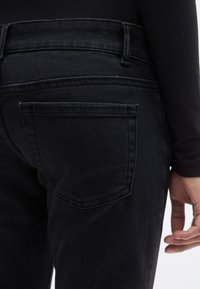 Μαύρο τζιν παντελόνι από τζιν με εφαρμοστή σχεδίαση, διαθέτει πίσω τσέπη και θηλιές για ζώνη. Ομαλή υφή και μίνιμαλ στυλ.