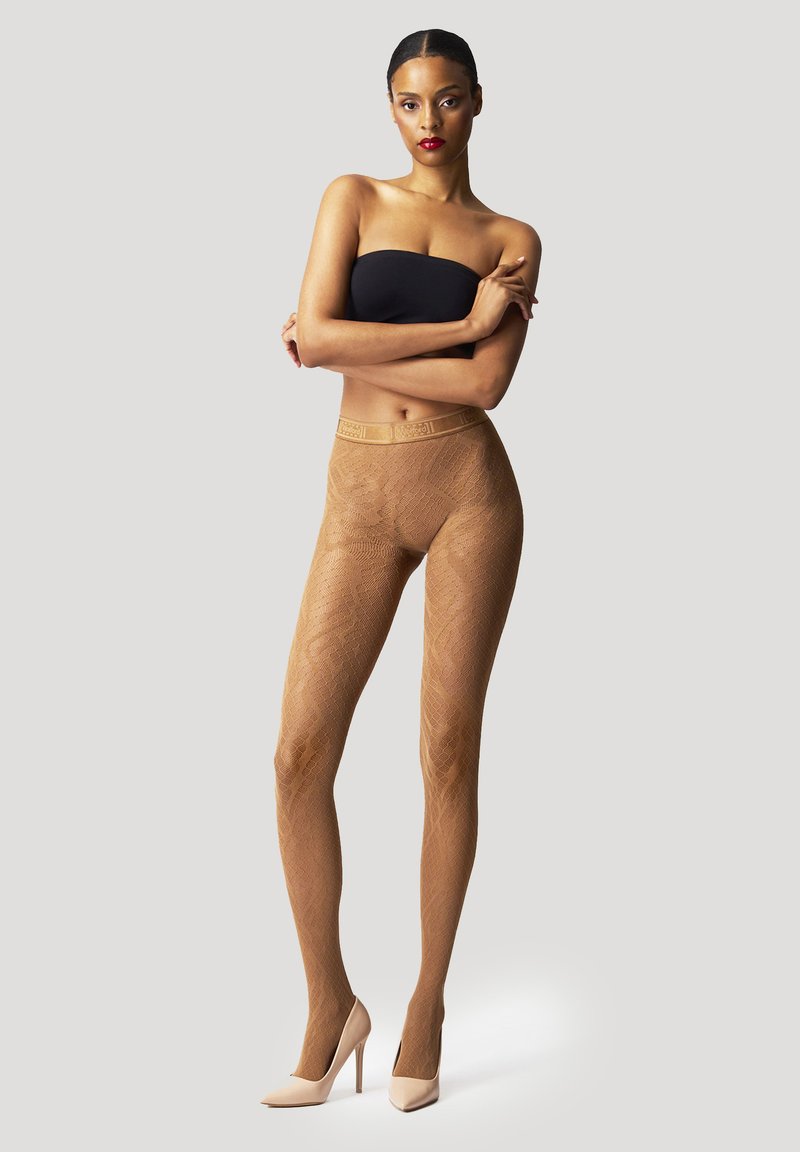 Beige gemusterte Strumpfhosen mit transparentem, strukturiertem Finish und einem breiten, dekorativen Bund, kombiniert mit hellfarbigen High Heels.