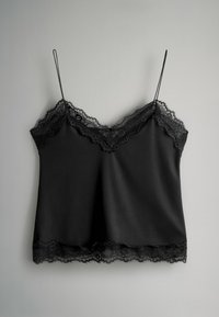 Melna kamisolē ar mežģīņu apdari gar izgriezumu un apakšu. Ir plānas regulējamas lences un gluda, zīdaini līdzīga satīna auduma faktūra.