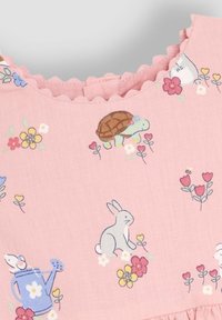 Vaaleanpunainen kangasmekko, jossa on kuvasto pupuista, kilpikonnista ja kukista. Aaltoreunainen kaula-aukko, jossa on pehmeissä väreissä floral kuvioita.
