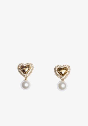 Gold heart-shaped earrings with clear crystals and white pearls, featuring the "GUESS" logo in the center of each heart.
