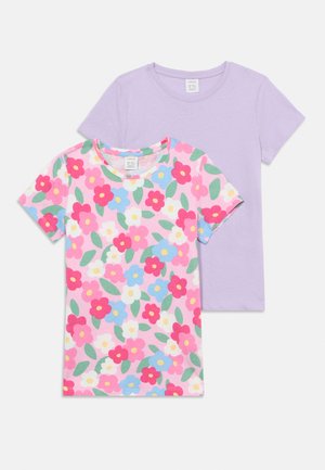 To t-shirts med korte ærmer, den ene ensfarvet lavendel og den anden med pink, blå, hvid og rød blomstermønster med grønne blade.