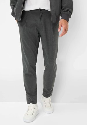 Mørkegrå skrædderbukser med en glat tekstur og frontfolder, parret med hvide low-top sneakers. Subtile syninger er synlige.