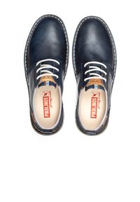 Scarpe in pelle blu navy con lacci bianchi, caratterizzate da una texture liscia, cuciture a contrasto e una soletta con marchio. Suole in gomma per una maggiore durata.