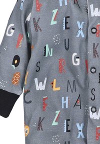 Bunt gemustertes Stoffhemd mit verstreuten Großbuchstaben in verschiedenen Schriftarten auf grauem Hintergrund; schwarze Bündchen an den Ärmeln.