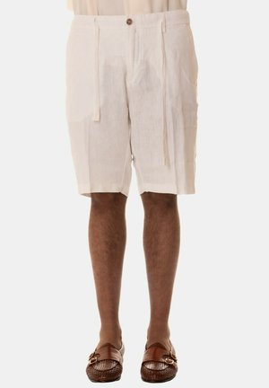 Pantaloni corti bianchi in lino con una vestibilità comoda, dotati di chiusura a bottono e lacci, abbinati a scarpe slip-on intrecciate marroni.