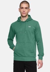 Felpa verde in pile con cappuccio regolabile, tasca frontale e polsini a costine. Presenta un piccolo logo Fila sul petto. Tessuto liscio.