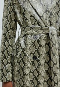 Python print trenchcoat in tinten van groen en beige, met een ceintuur, twee knopen en een glanzende textuur.