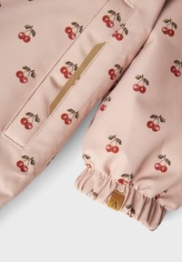 Roze jack met kersenprint, elastische manchetten en een klein patch-pocket. Het materiaal lijkt glad te zijn, met een verscheidenheid aan kersendesigns en groene bladeren.