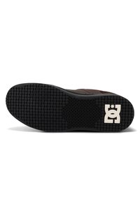 Schuhsohle mit quadratischem, schwarzem Profil und weißem DC Shoes-Logo nahe der Ferse, braunes Obermaterial teilweise sichtbar.