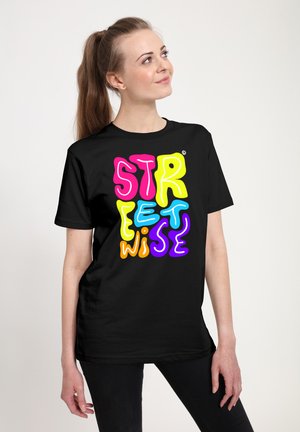 Ung kvinde med hestehale iført en sort t-shirt med farverig tekst "Streetwise" i fede, legende skrifttyper.
