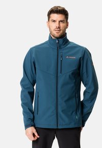 Veste softshell teal avec col montant, fermeture éclair à l'avant et deux poches latérales. Présente le logo Vaude et des accents en Velcro sur les poignets.