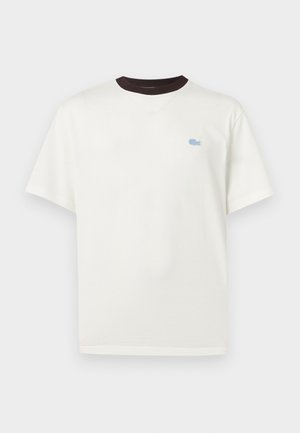 Witte t-shirt met korte mouwen, zwarte ronde hals en klein lichtblauw krokodillenlogo op de linkerborst.