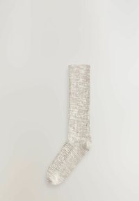 Sølvmetallic strikket sok med ribbet tekstur, mellemlang længde, rund tå og blød finish, vist mod en ensfarvet baggrund.
